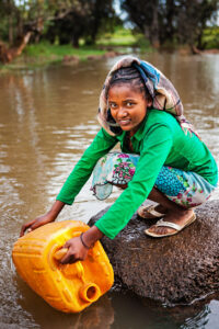 African girl is taking water from the river, Ethiopia, Africa